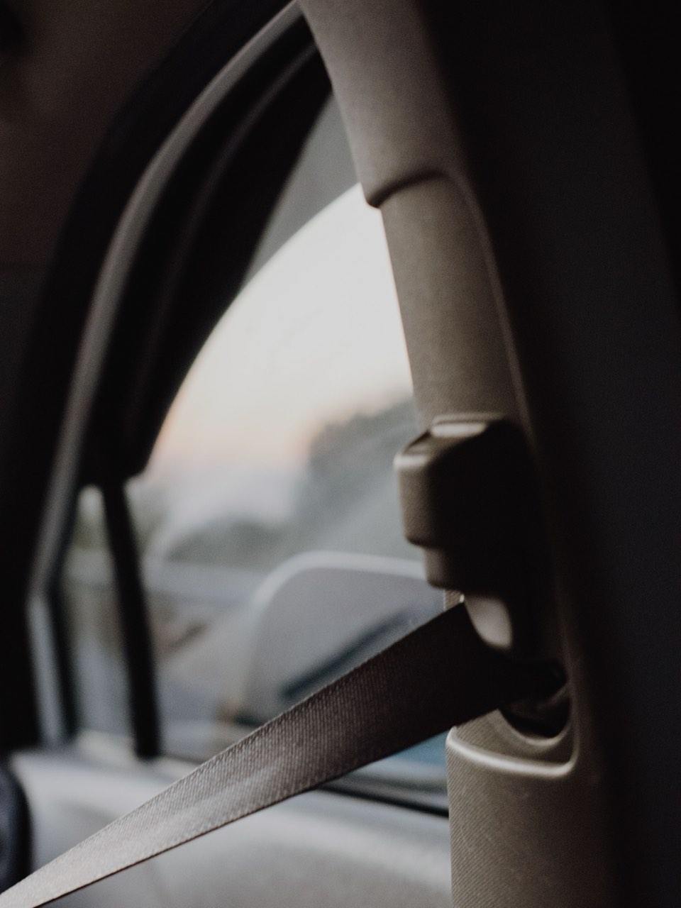 Seat belt webbing running through the height adjuster on a vehicle B-pillar, with the woven belt surface and anchor point in close view.